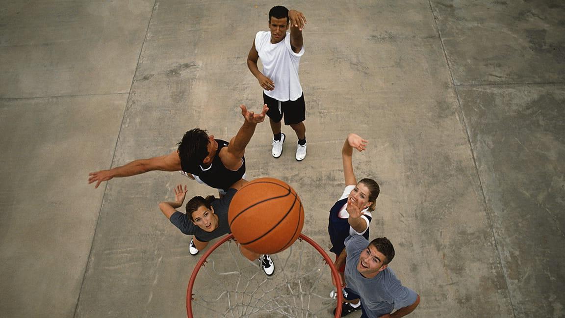 diverse friends playing basketball outdoors
