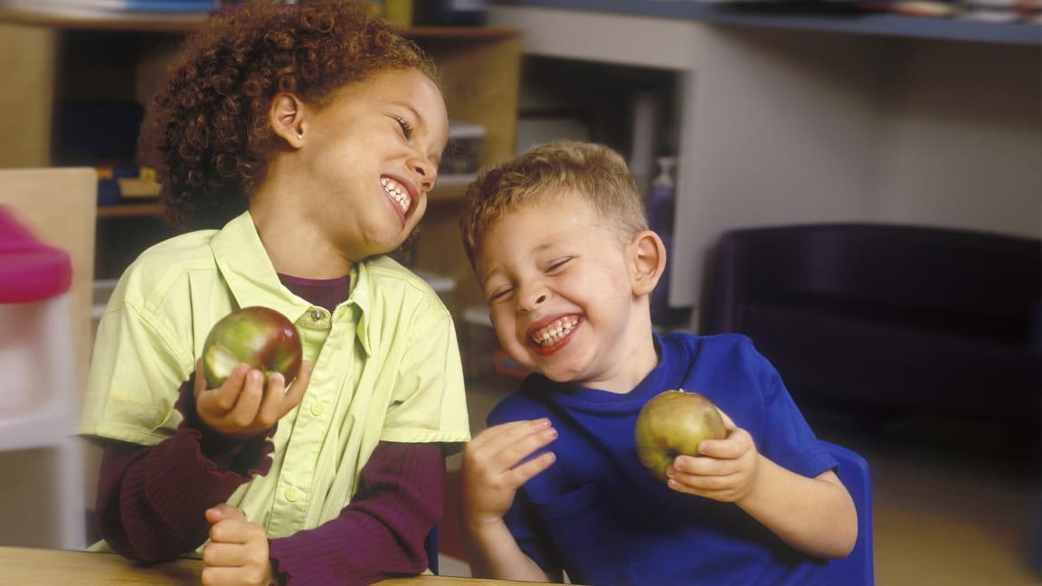 boys laughing while eating apples
