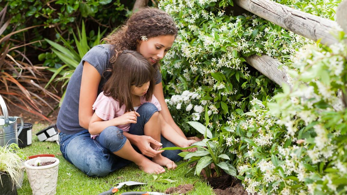 mother and daughter planting in garden