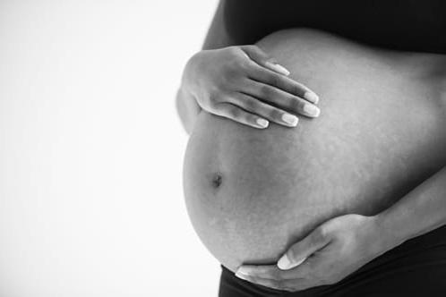 View of just a woman's pregnant belly with her hands holding on gently