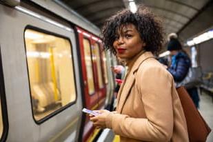 woman holding her phone about to board a train in underground station
