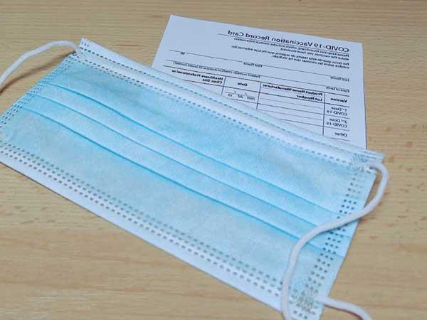 COVID vaccination card with blue protective mask