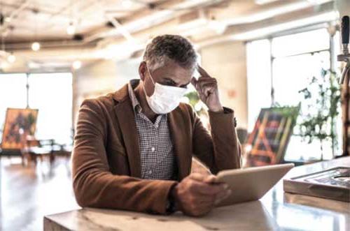 man wearing face mask while reading tablet